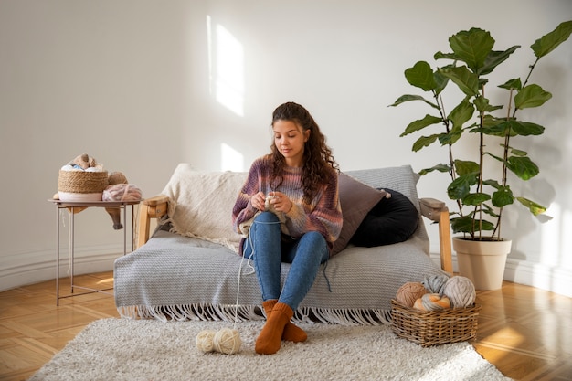 Full shot woman knitting at home