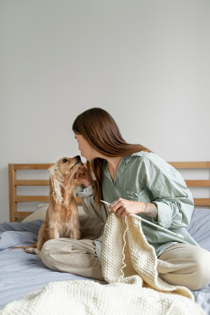 Full shot woman knitting with dog