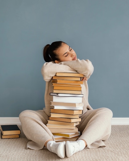 Full shot woman laying on books stack