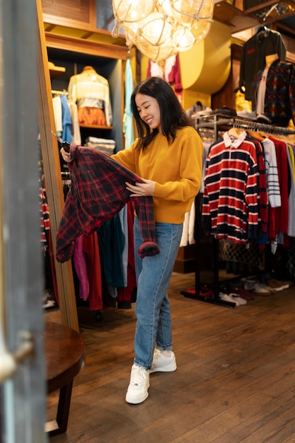 無料写真 古着屋で服を見ているフルショットの女性