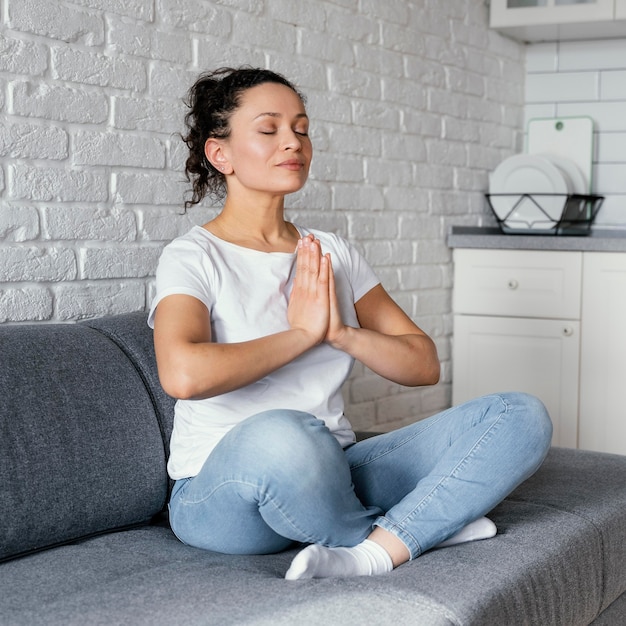 Free photo full shot woman meditating on couch