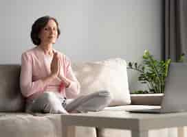 Бесплатное фото Полный выстрел женщина медитирует в помещении