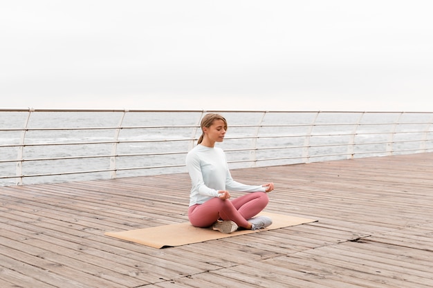 Full shot woman meditating on mat