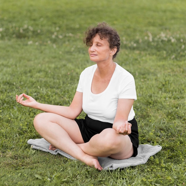 屋外で瞑想するフルショットの女性