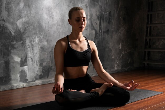 Full shot woman meditating posture indoors