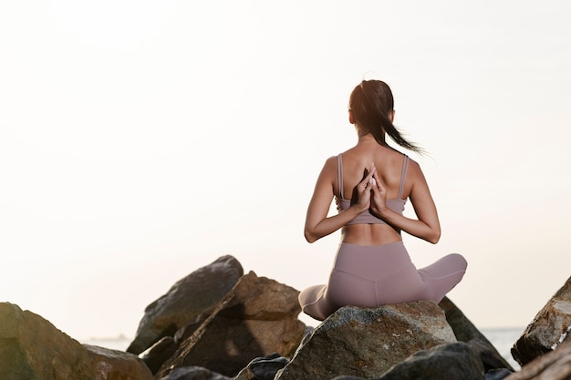 Full shot woman meditating on rocks