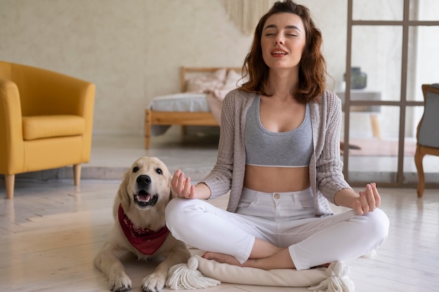 Full shot woman meditating with dog