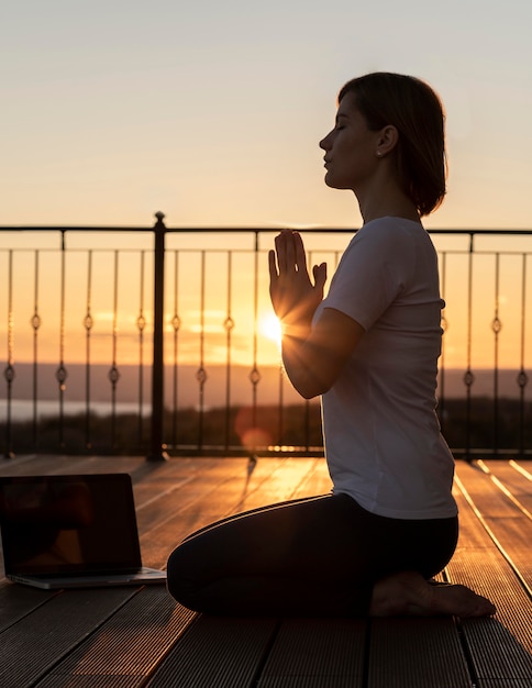 Full shot woman meditating with laptop