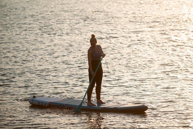 Free photo full shot woman on paddleboard