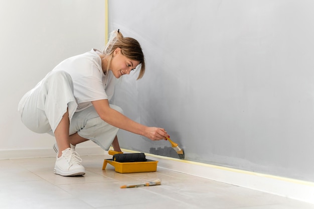 Full shot woman painting wall