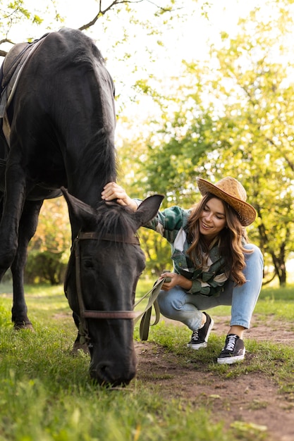 屋外で馬をかわいがるフルショットの女性