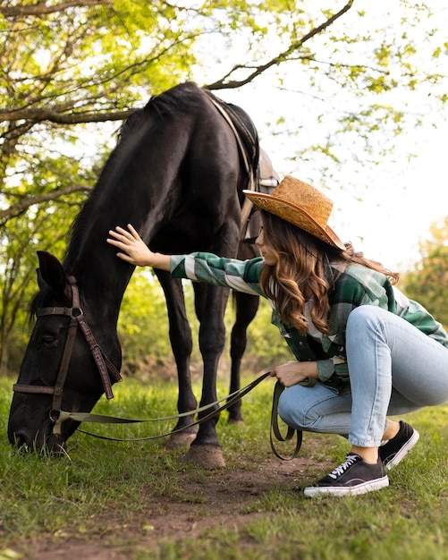 full shot woman petting horse