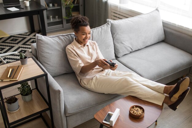 Full shot woman playing on couch