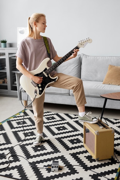 Full shot woman playing the guitar at home