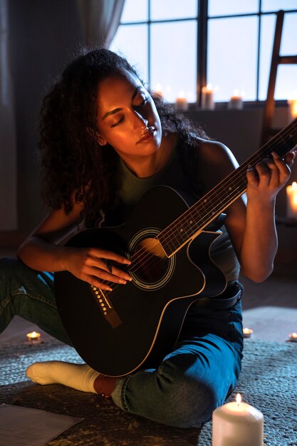 自宅でギターを弾くフルショットの女性