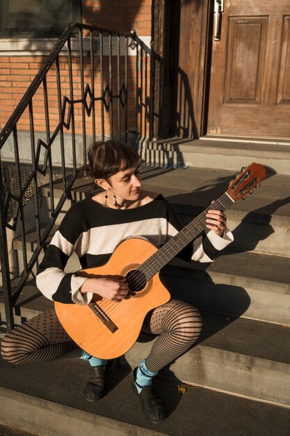 屋外でギターを弾くフルショットの女性