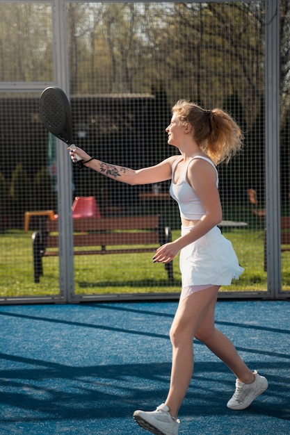 Free photo full shot woman playing paddle tennis