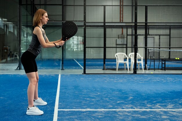 Полный снимок женщины, играющей в паддл-теннис