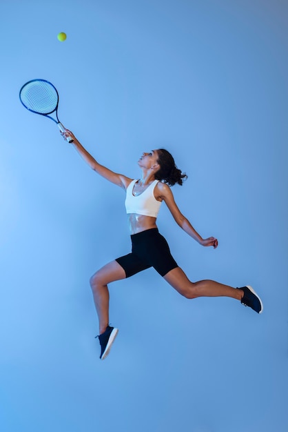 Женщина в полный рост играет в теннис с ракеткой