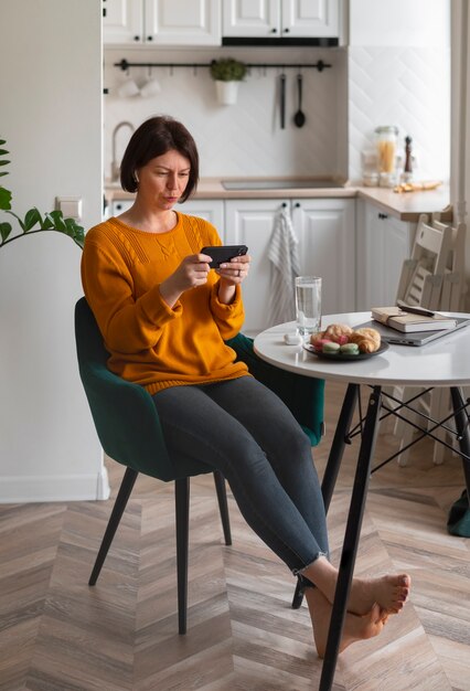 Full shot woman playing with her phone