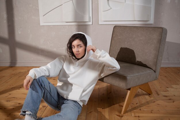 Full shot woman posing on floor with hoodie