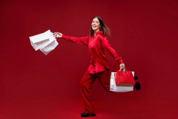 Полный снимок женщины, позирующей с хозяйственными сумками