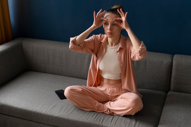 Full shot woman practicing facial yoga