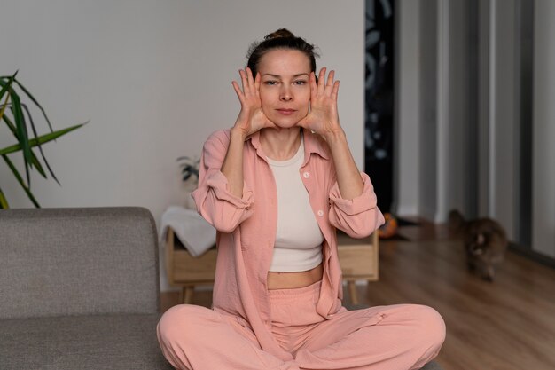 Full shot woman practicing facial yoga