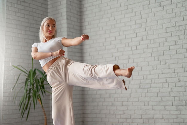 Full shot woman practising tai chi indoors