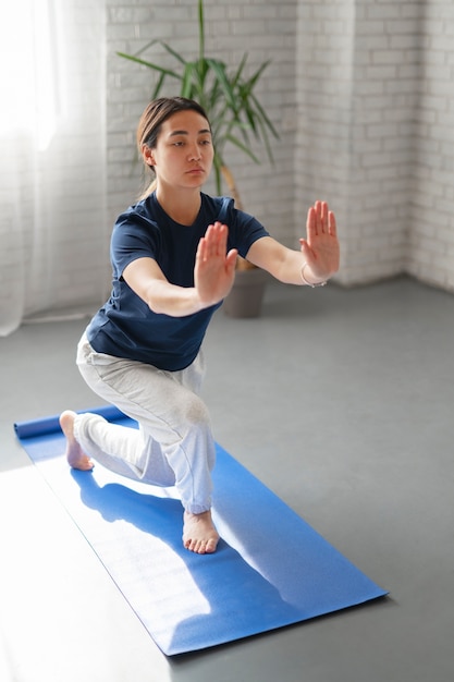 Foto gratuita donna del colpo pieno che pratica il tai chi all'interno