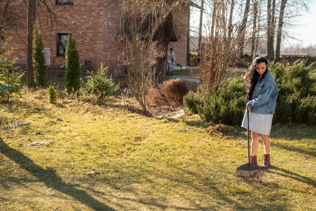 Free photo full shot woman raking outdoors