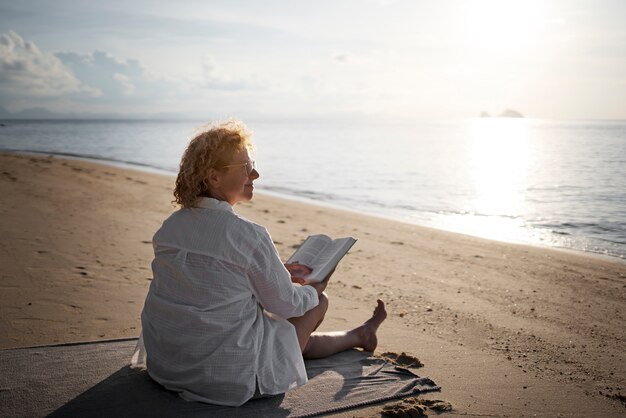 Full shot woman reading on beach