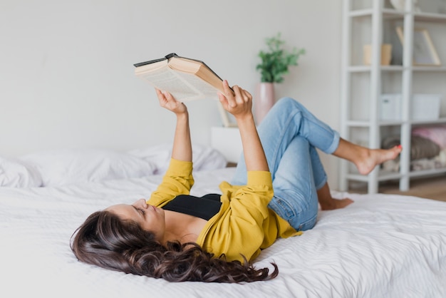 Free photo full shot woman reading in bed