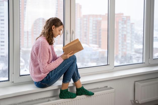 Free photo full shot woman reading book at home