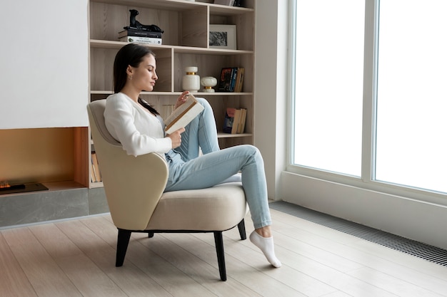 Full shot woman reading on chair