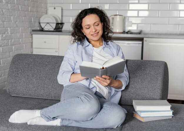 Full shot woman reading on couch