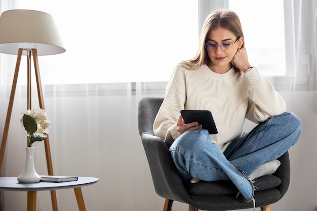 Foto gratuita donna a figura intera che legge rivista digitale