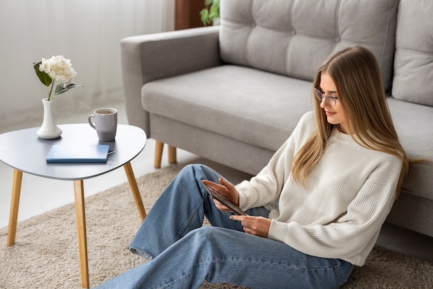 Foto gratuita donna a figura intera che legge rivista digitale