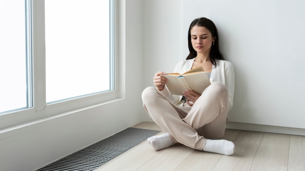 Full shot woman reading on floor