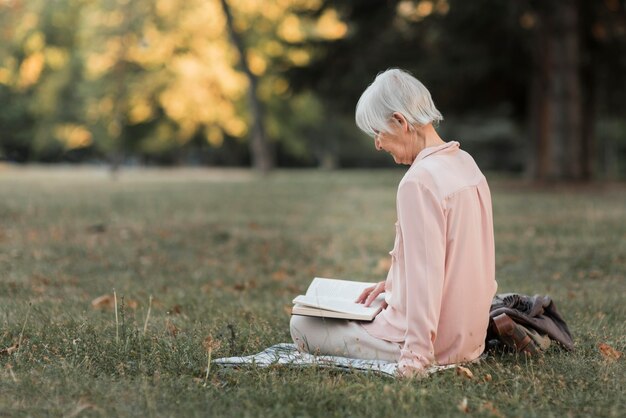 Full shot woman reading in nature
