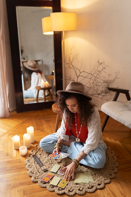 Free photo full shot woman reading tarot at home