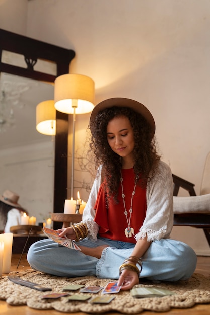 Free photo full shot woman reading tarot at home