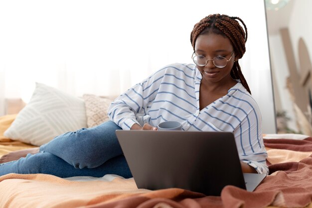 Full shot woman relaxing with laptop in bed