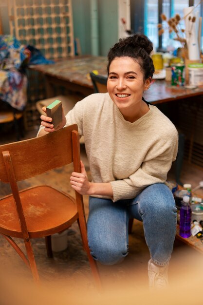 Full shot woman restoring wooden chair