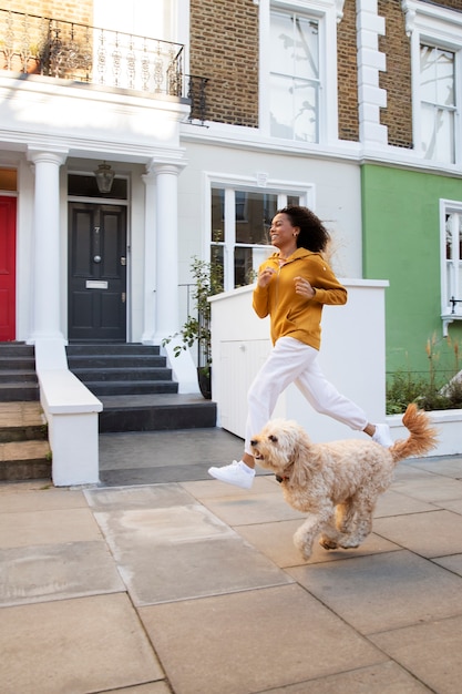 Full shot woman running with dog outdoors