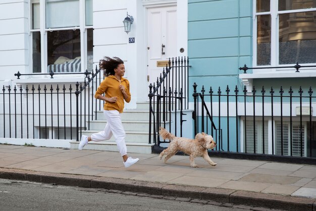 Full shot woman running with dog outdoors