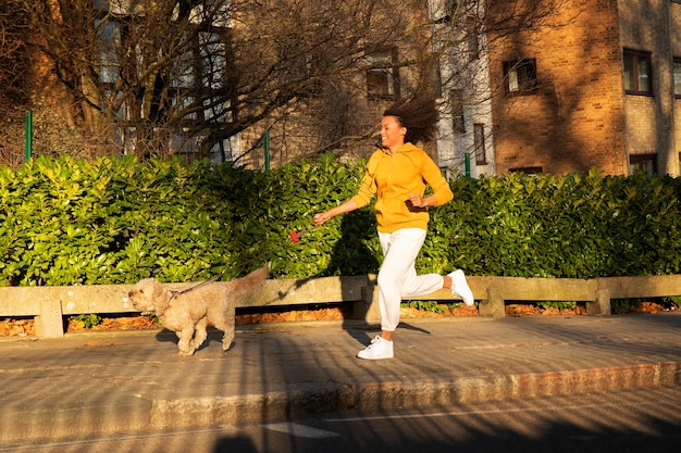 Full shot woman running with dog outdoors