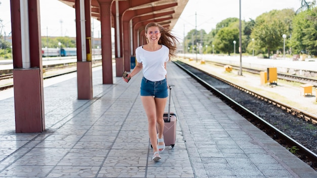 Full shot woman running with luggage in train station