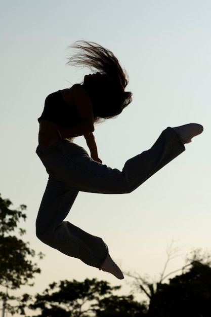 無料写真 夕暮れ時にジャンプするフルショットの女性のシルエット