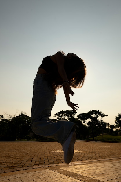 Foto gratuita siluetta della donna del colpo pieno che salta al tramonto